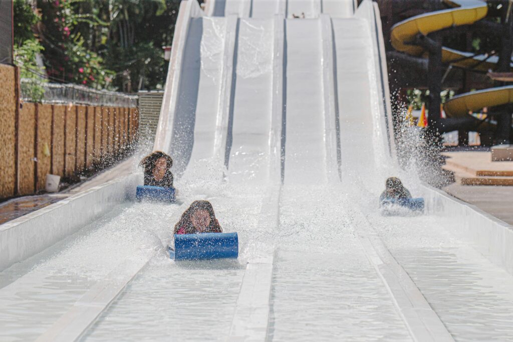 Children having fun on a thrilling water slide at the park during a sunny summer day.